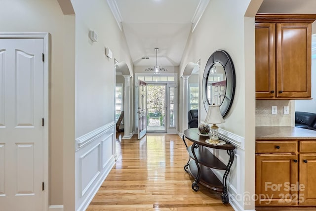 1151 Donelea Ln NW, Concord, NC 28027 - hallway featuring a wainscoted wall, light wood-style flooring, arched walkways, decorative columns, and a decorative wall