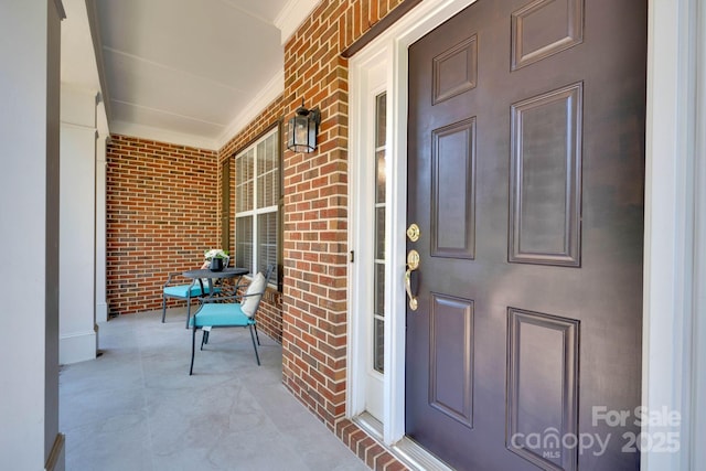 entrance to property featuring brick siding and covered porch