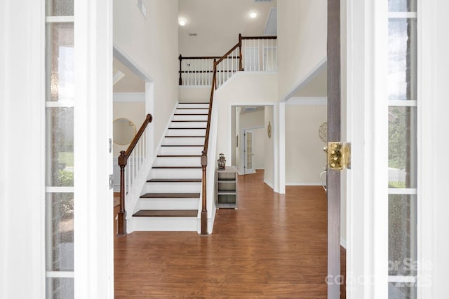 entrance foyer featuring stairs, wood finished floors, a towering ceiling, and baseboards