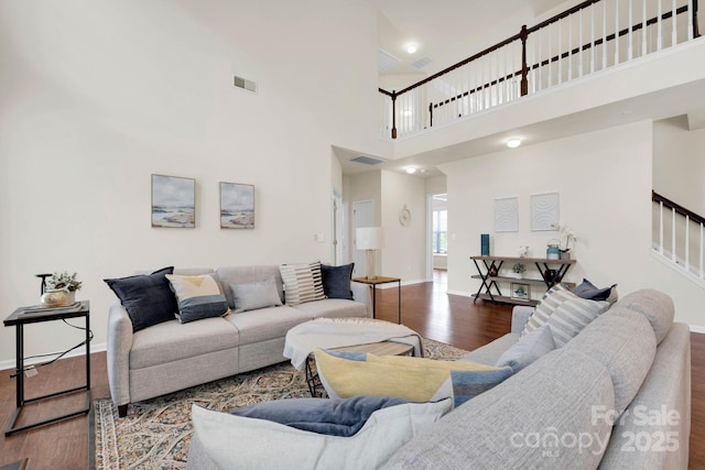 living room with stairway, baseboards, wood finished floors, and visible vents