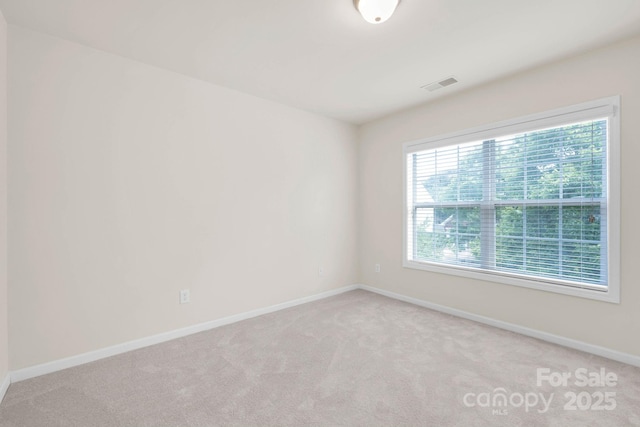 spare room featuring baseboards, visible vents, and light colored carpet