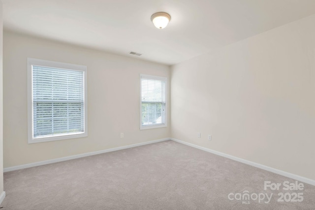 empty room with baseboards, visible vents, and carpet floors