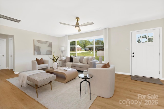 living room with ceiling fan, baseboards, visible vents, and light wood-style flooring