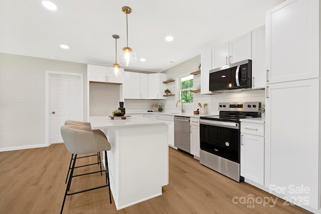 kitchen with stainless steel appliances, tasteful backsplash, light wood-style floors, open shelves, and light countertops