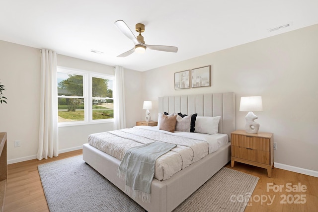 bedroom featuring baseboards, light wood finished floors, and visible vents