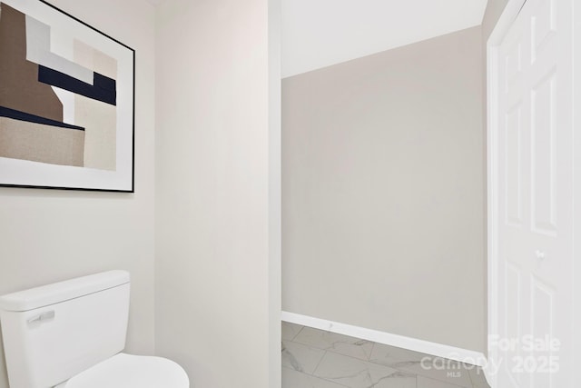 bathroom with marble finish floor, toilet, and baseboards