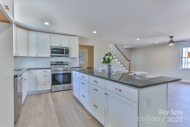 3424 Walker Cir, Lenoir, NC 28645 - kitchen featuring white cabinets, stainless steel appliances, light wood-style flooring, and backsplash