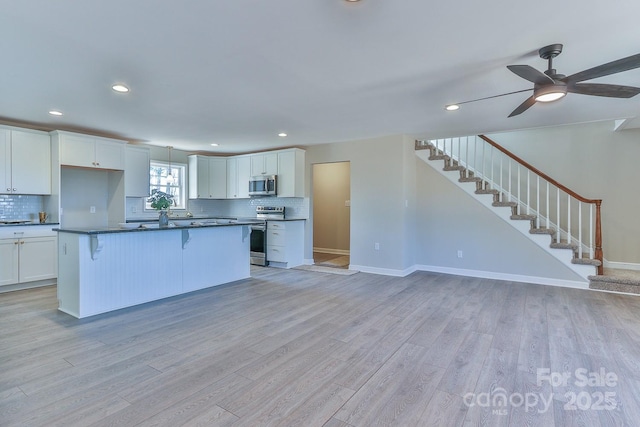3424 Walker Cir, Lenoir, NC 28645 - kitchen with dark countertops, appliances with stainless steel finishes, a kitchen bar, and light wood-style floors