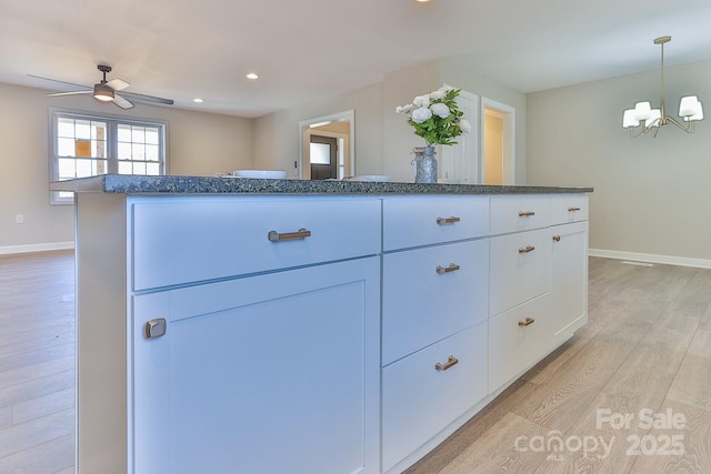 3424 Walker Cir, Lenoir, NC 28645 - kitchen featuring ceiling fan with notable chandelier, dark stone countertops, light wood finished floors, white cabinetry, and baseboards