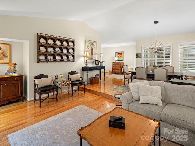 living room with lofted ceiling, wood finished floors, and a notable chandelier