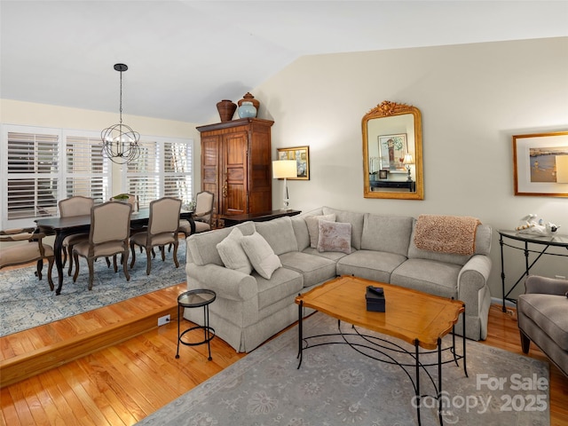 living room with light wood-type flooring, vaulted ceiling, and a chandelier