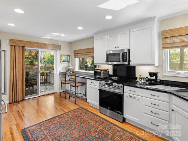 kitchen featuring dark countertops, stainless steel appliances, and white cabinetry