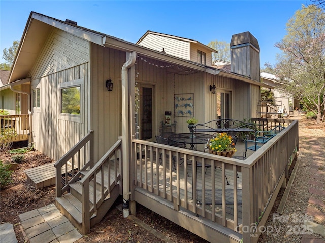 back of house with outdoor dining space, a chimney, and a deck
