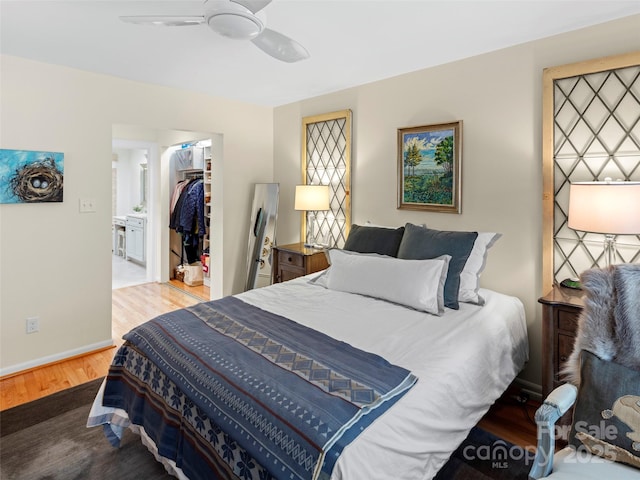 bedroom with baseboards, a ceiling fan, wood finished floors, a closet, and a walk in closet
