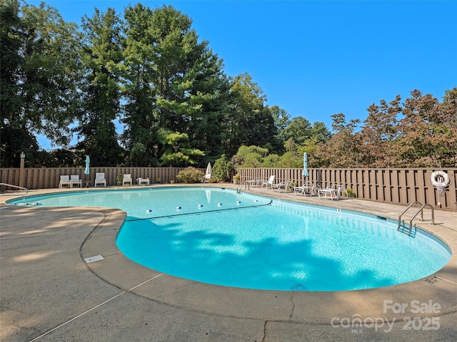 community pool with fence and a patio area