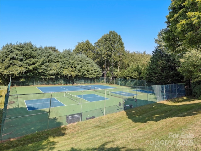 view of tennis court featuring fence and a yard