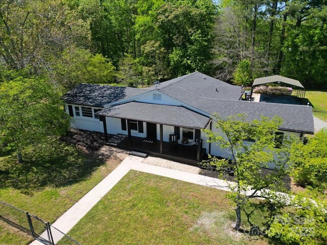 view of front of house featuring roof with shingles, a porch, a front lawn, and a carport