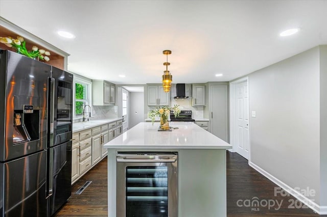 kitchen featuring wall chimney exhaust hood, appliances with stainless steel finishes, beverage cooler, and light countertops