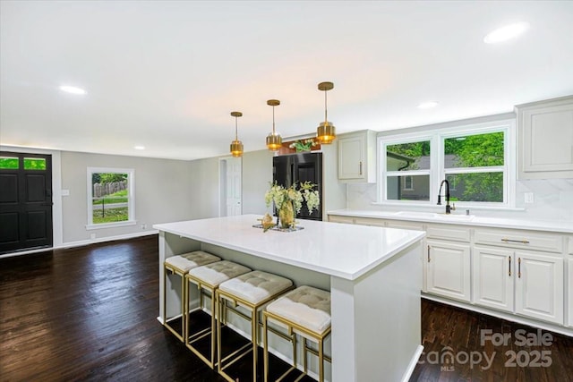 kitchen with recessed lighting, light countertops, a sink, freestanding refrigerator, and a kitchen island