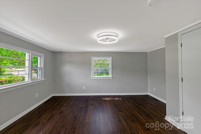 unfurnished room featuring baseboards, ornamental molding, and dark wood-type flooring