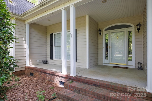 entrance to property featuring crawl space, a shingled roof, and covered porch