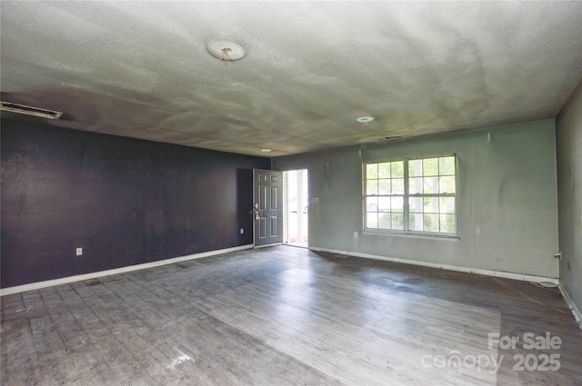 spare room featuring baseboards, visible vents, and wood finished floors