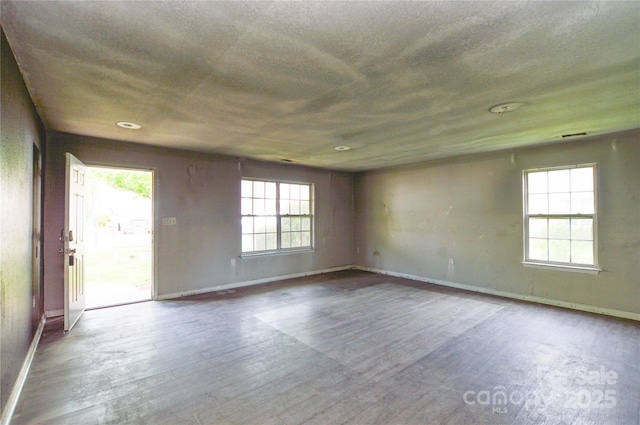 empty room featuring baseboards, wood finished floors, and a textured ceiling