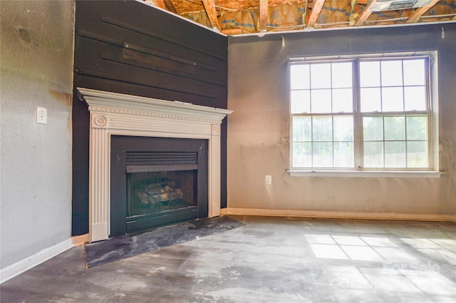 unfurnished living room with a fireplace with flush hearth, concrete flooring, and baseboards