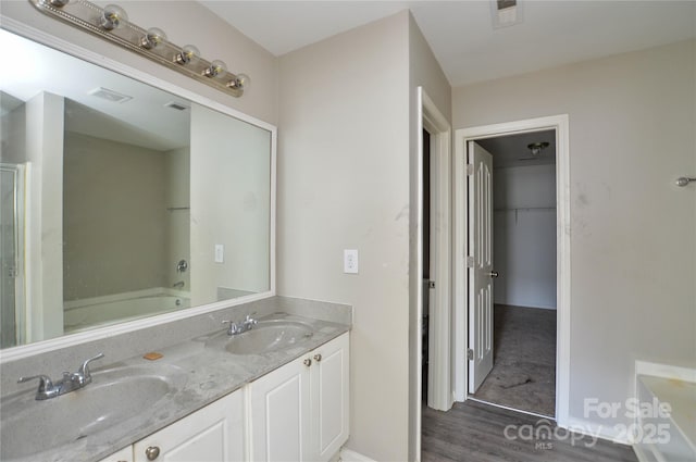 full bathroom featuring double vanity, wood finished floors, visible vents, and a sink