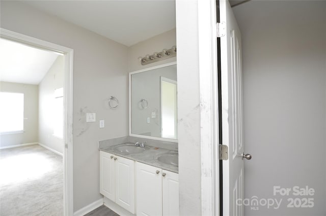 bathroom featuring baseboards, double vanity, and a sink