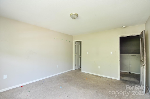 unfurnished bedroom featuring baseboards, carpet floors, a walk in closet, and a closet
