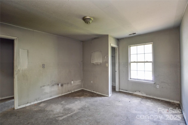 carpeted spare room with visible vents and baseboards