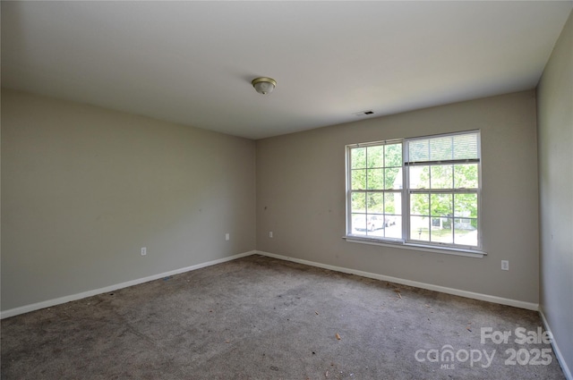 empty room with baseboards, visible vents, and carpet flooring