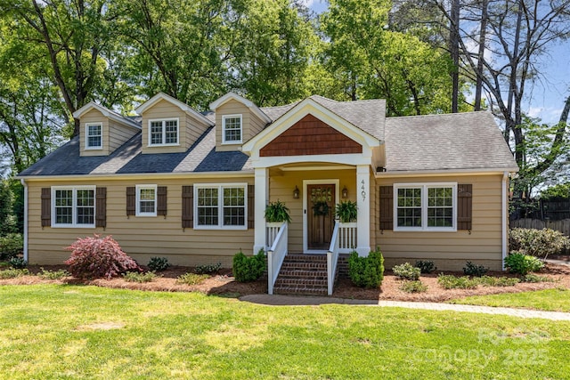 view of front facade featuring a front lawn, fence, and a shingled roof