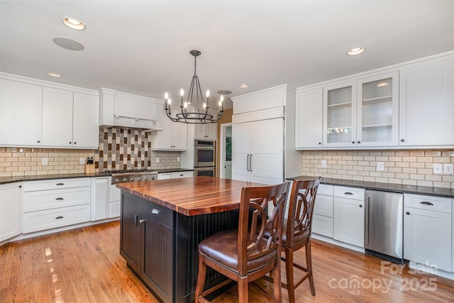 kitchen with wood counters, appliances with stainless steel finishes, a chandelier, white cabinetry, and recessed lighting