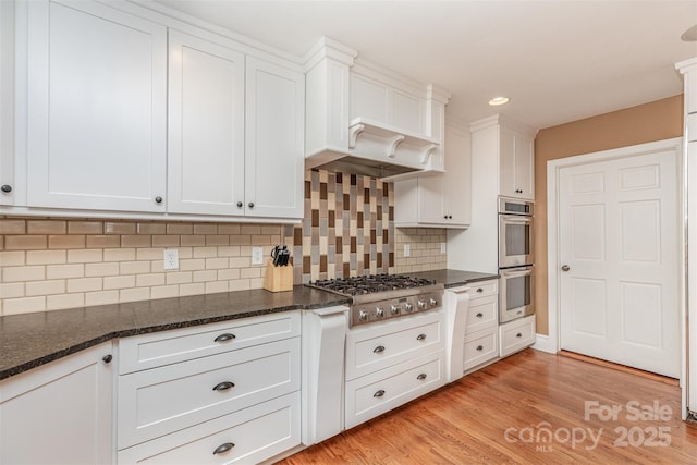 kitchen featuring stainless steel appliances, white cabinets, decorative backsplash, light wood finished floors, and recessed lighting