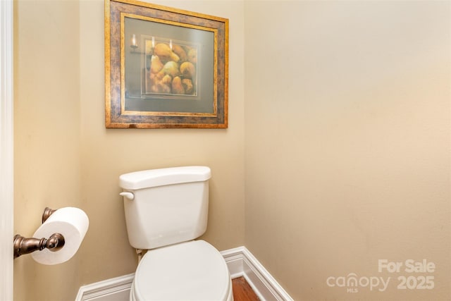 half bath with baseboards and toilet