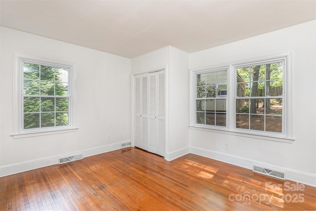 unfurnished bedroom with baseboards, hardwood / wood-style floors, and a closet