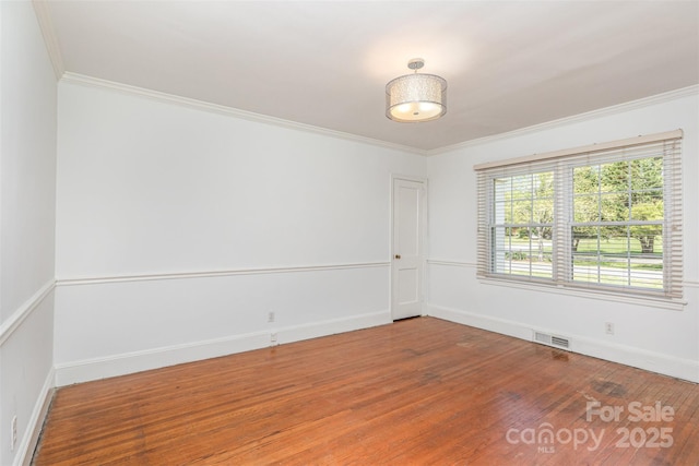 spare room with wood finished floors, crown molding, and baseboards