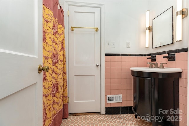 bathroom with tile walls, a wainscoted wall, and vanity