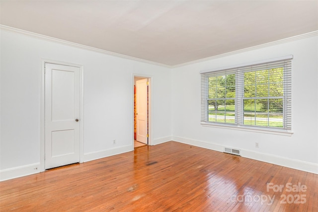 spare room featuring ornamental molding, light wood-style floors, and baseboards