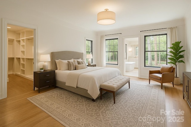 bedroom with light wood-type flooring, a walk in closet, and connected bathroom
