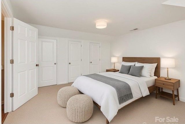 bedroom with light carpet, multiple closets, and baseboards