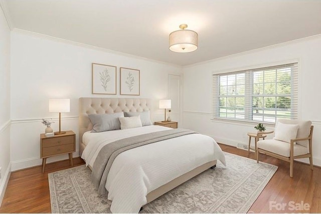 bedroom featuring ornamental molding, wood finished floors, and baseboards