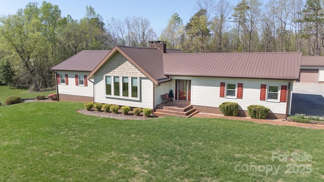 ranch-style house featuring a chimney, a front yard, and metal roof