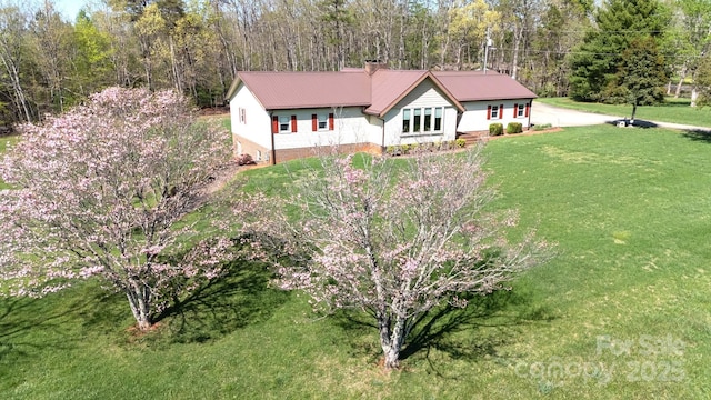 view of front of house with a chimney, metal roof, and a front lawn