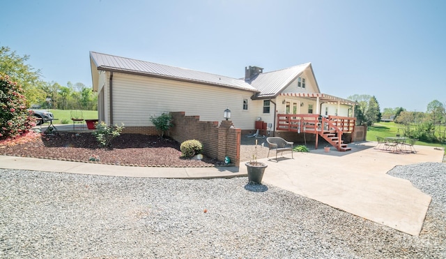 back of house with a patio, a wooden deck, and metal roof