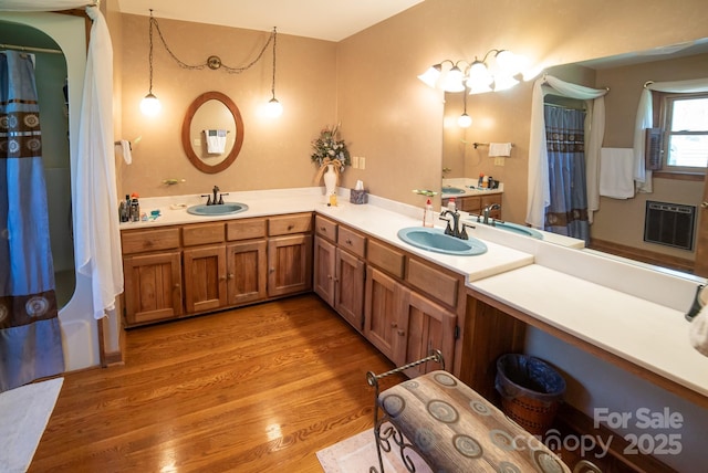 bathroom with double vanity, a sink, and wood finished floors