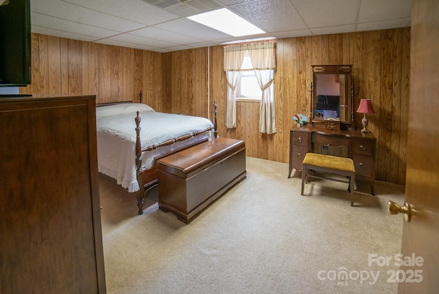 carpeted bedroom featuring wood walls and a paneled ceiling
