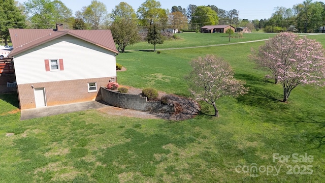 view of property exterior featuring brick siding, a yard, a chimney, and metal roof